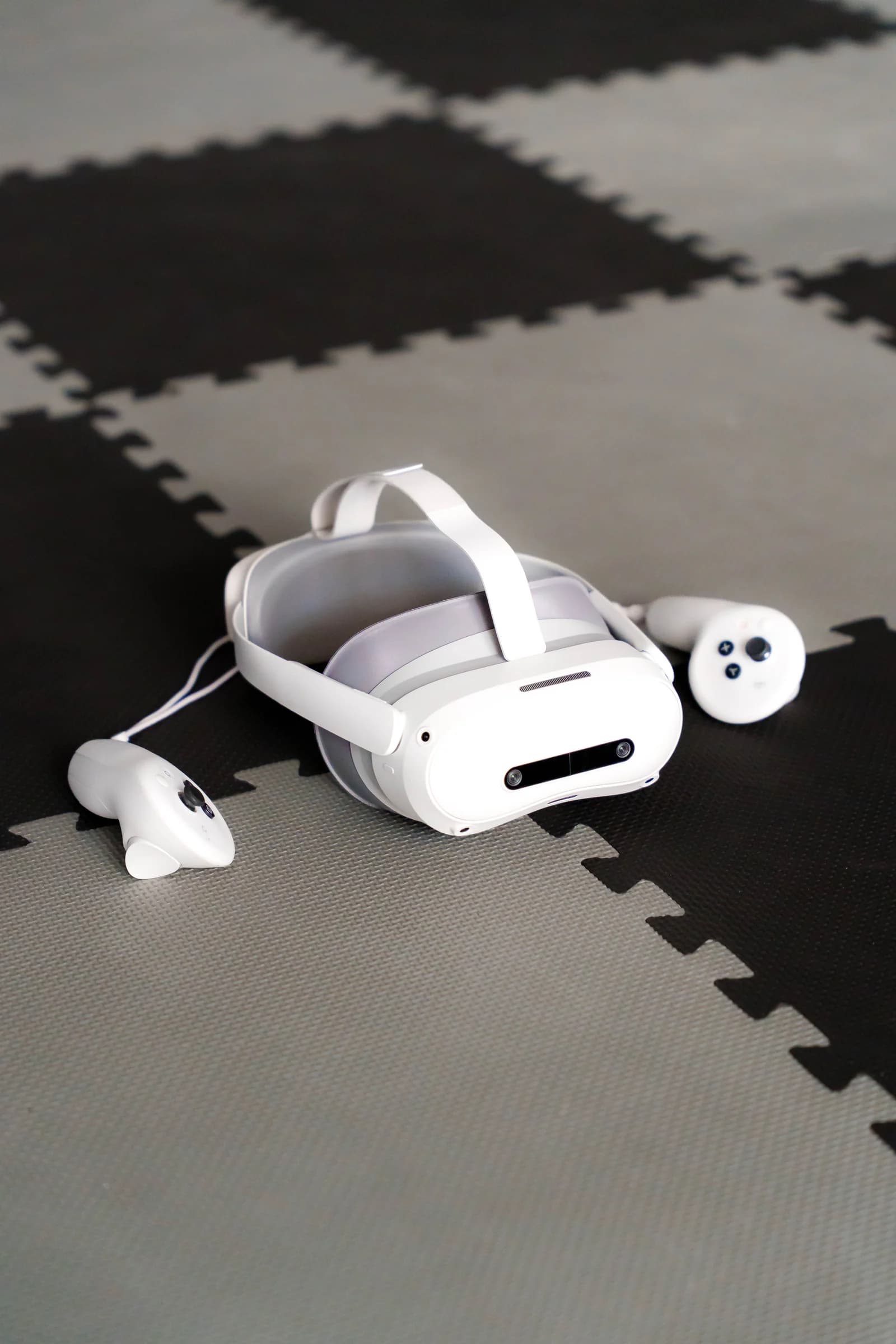 Headset de realidade virtual e dois comandos pousados no chão de espuma da arena