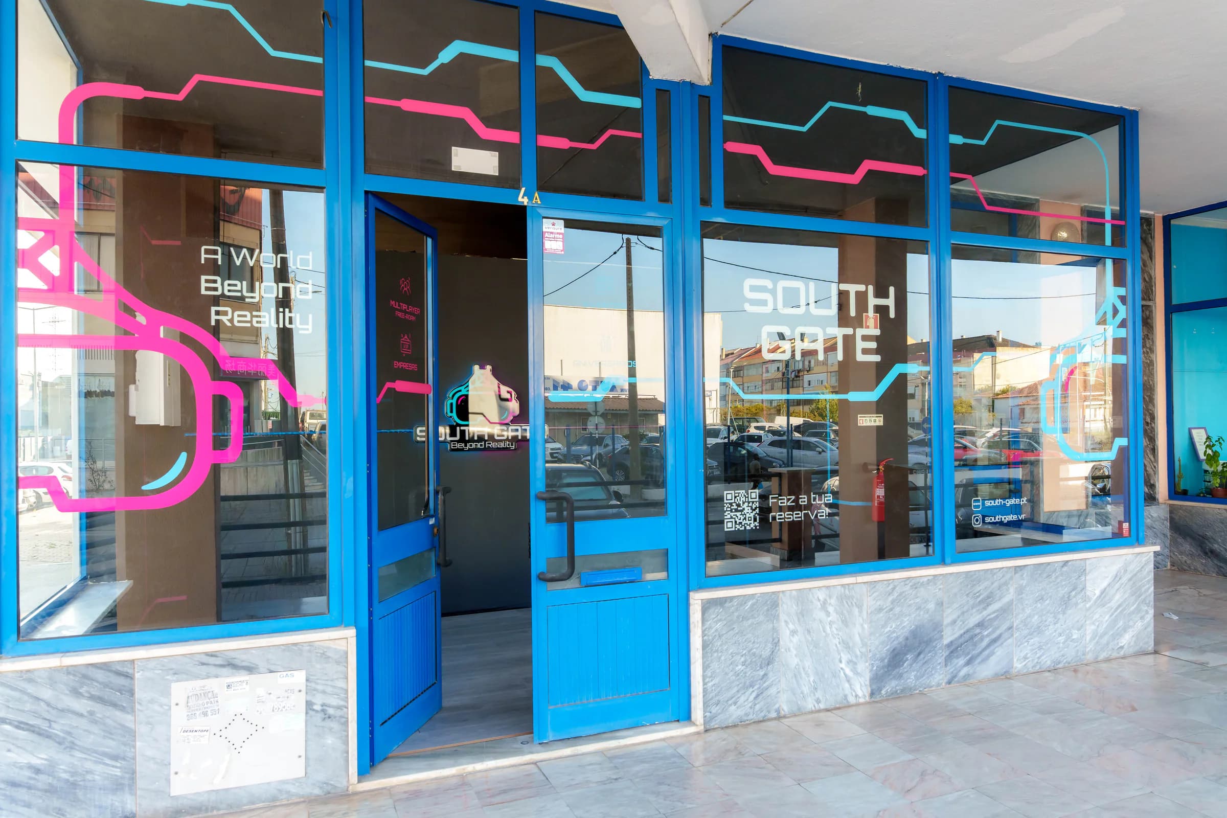 Fachada da South Gate com as portas azuis abertas e o lema "A World Beyond Reality" na montra