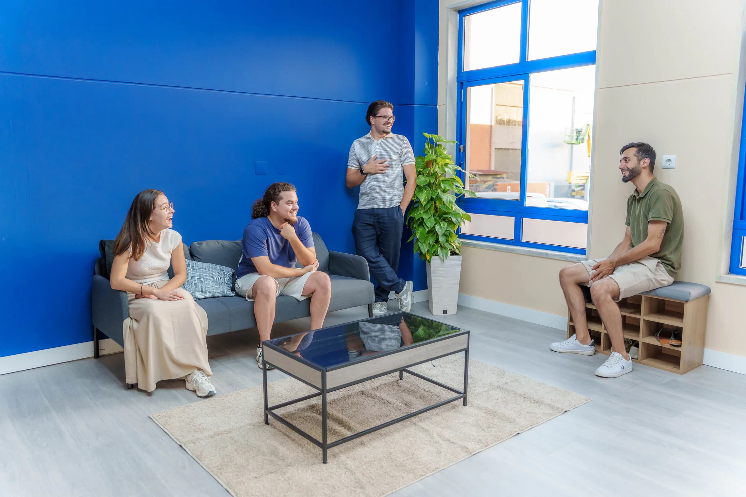 Quatro pessoas a conversar na zona lounge, sentadas no sofá junto à parede azul